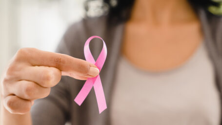Cropped photo of caucasian woman holding pink ribbon for fighting against breast cancer, supporting women on world cancer day